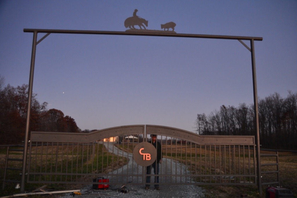 Ornamental driveway gate for ranch entrance by JDR Metal Art. Created from steel with customized copper ornaments that are powered by an electric gate opener with keypad.