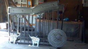 Picture of custom gate with arched top and sheet metal adorned with clavos and a ranch brand silhouette.