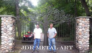 These are custom built driveway gates that were plasma cut by jdr metal art. They are mounted to stone columns and have a plasma cut metal art tree design.