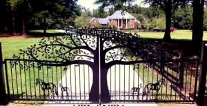 Driveway security gates with oak trees and horse silhouettes.