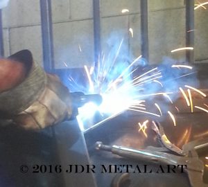 Metal fabricator welding an atlanta iron driveway gate.