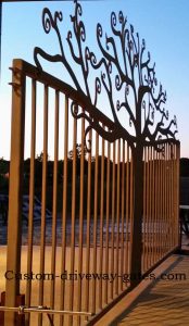 Artistic driveway gate with single swing curly tree design.