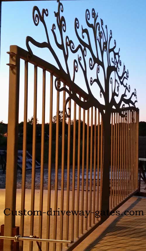 Artistic driveway gate with curly tree design.