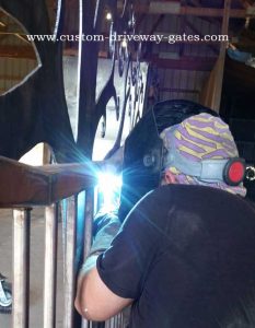 Welding on plasma cut tree silhouette to driveway gate.