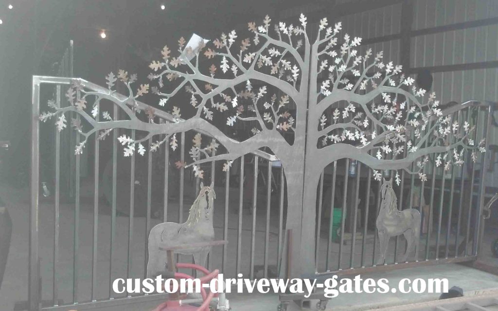 Rustic California driveway gates with tree and horse design.
