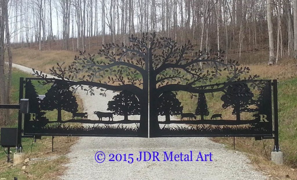 Tree of Life Driveway Gate at ornamental entrance to fenced property with gravel driveway.