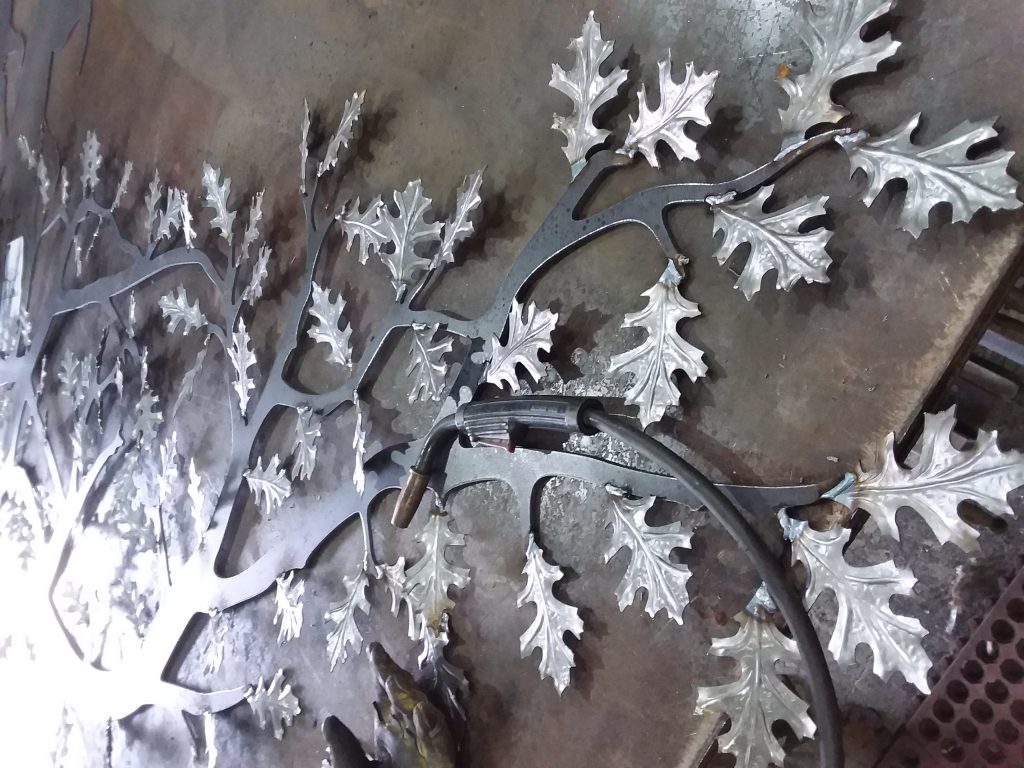 Photo of progress welding iron leaves on tree with iron welder.