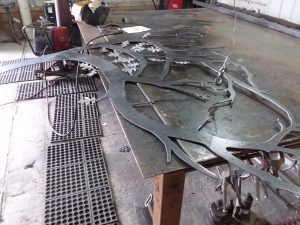 Custom builder of driveway gate with photo of progress welding leaves.