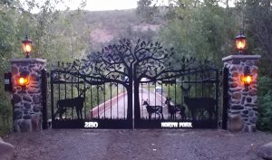 A driveway gate with customized driveway gates with tree and deer theme.