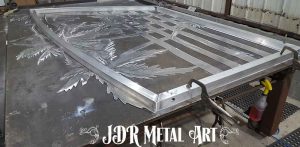 Aluminum gate panel laying on welding table.