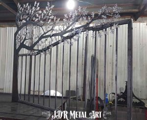 Iron tree gate stood upright on welding table during fabrication.