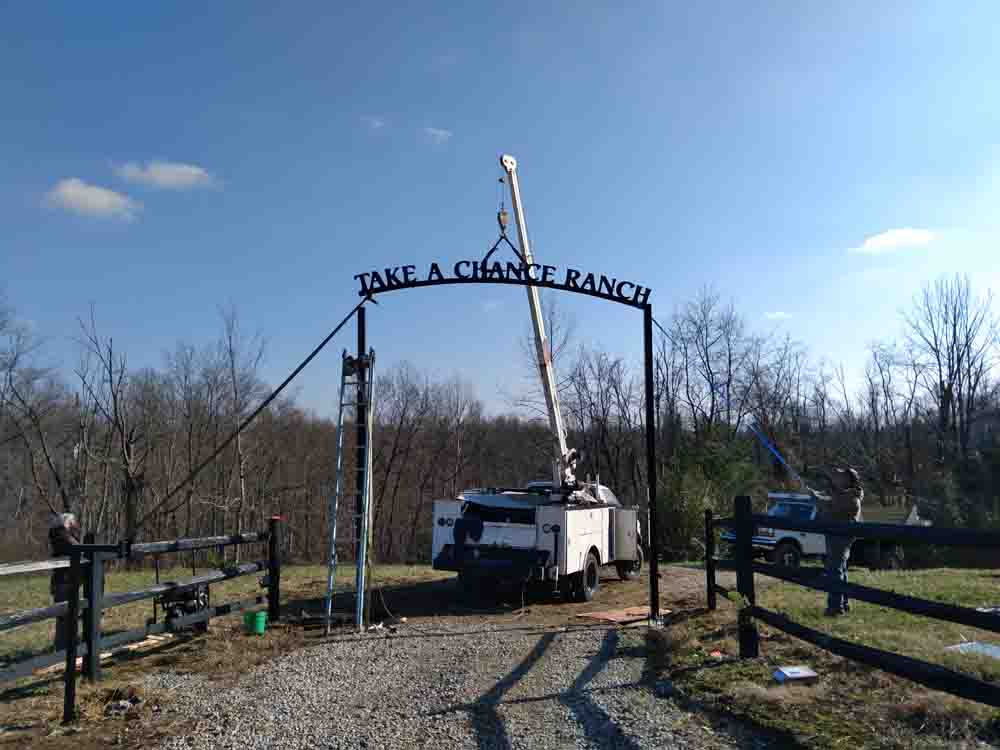 Hanging a driveway gate overhead arch piece for Take A Chance Ranch