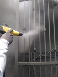 Image of a powder coated driveway gate being sprayed.