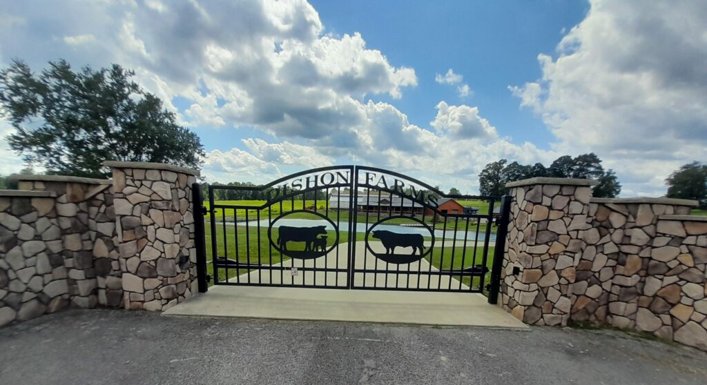 Custom farm driveway gates hung from stone columns.