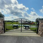 Custom farm driveway gates hung from stone columns.