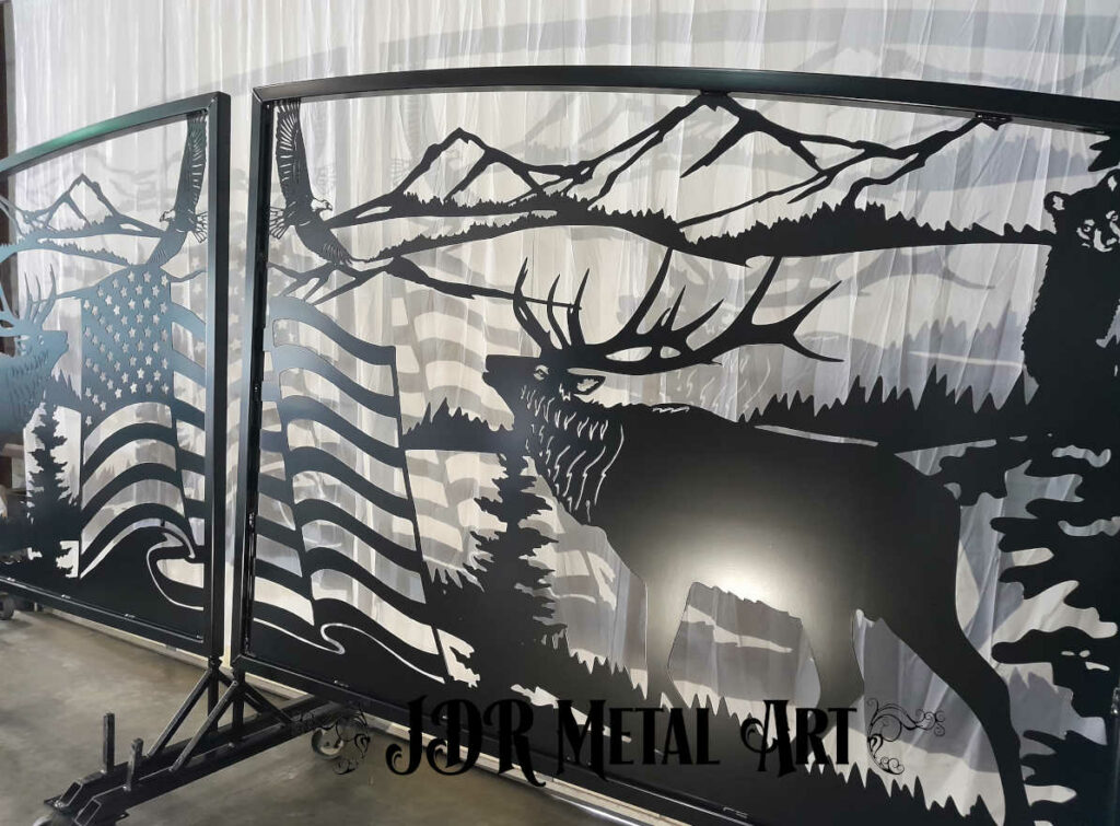 Driveway gates with wildlife theme including elk bear and bald eagles in the mountains with a pine forest.