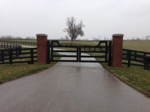 Driveway gate design idea with classy arched top rail, rectangle tubing either steel or aluminum with brick columns.