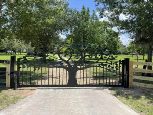 Driveway gate design idea with tree and pickets.