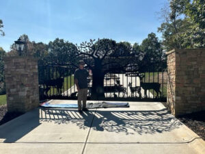 Cumming Georgia driveway gates with ornamental gate design idea featuring deer and an oak tree with pickets, and also stone columns.