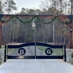 Atlanta driveway gates with wrought iron and black powder coated finish with wood arch overhead and stone columns, and also concrete driveway and gate openers.