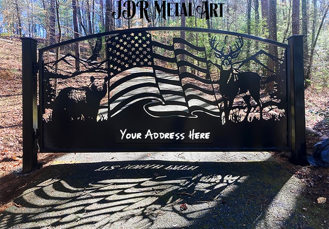 A driveway gate Atlanta made from steel with an arched top and two 6x6 gate posts. The gate design idea includes wildlife such as whitetail deer, a black bear, a bald eagle, a flag and the North Georgia mountains in the background of the scene.