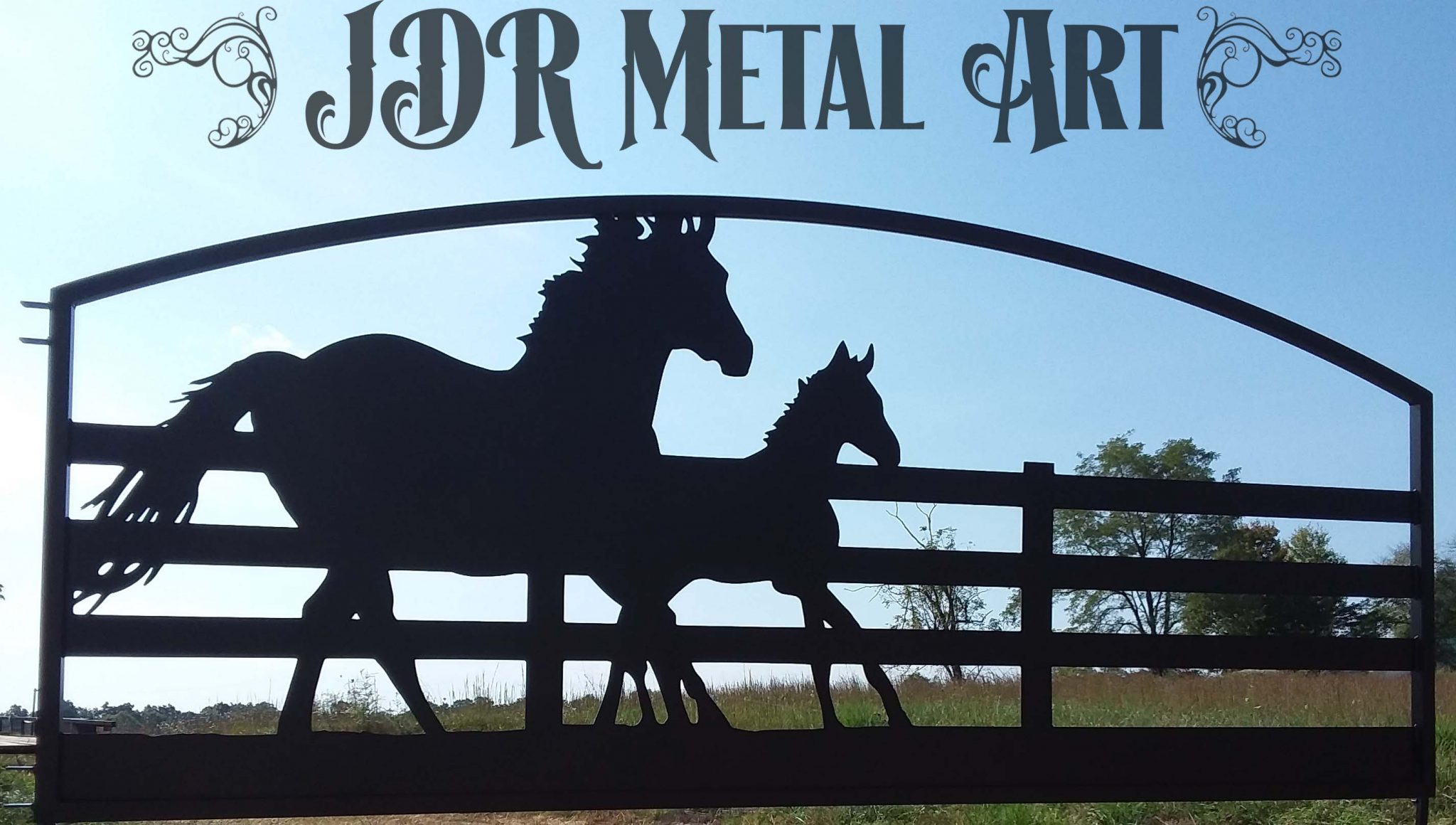 A beautifully crafted custom driveway gate with an arched top showcases a horse-themed design. Two detailed horse figures stand at the center, their forms emphasizing strength and elegance. The gate’s robust metal structure and flowing curves blend seamlessly with its artistic theme, making it both a functional entryway and a striking visual statement.