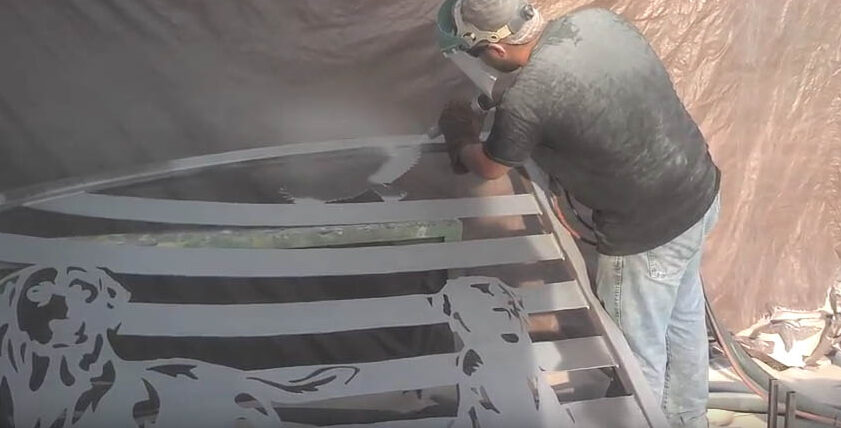 worker powder coating a custom driveway gate