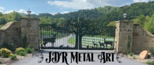 Set of driveway gates with custom metal decorative elements and ornamental designs of deer beneath an oak tree with pickets, custom hinges and an automatic gate opener system hung by JDR Metal Art.