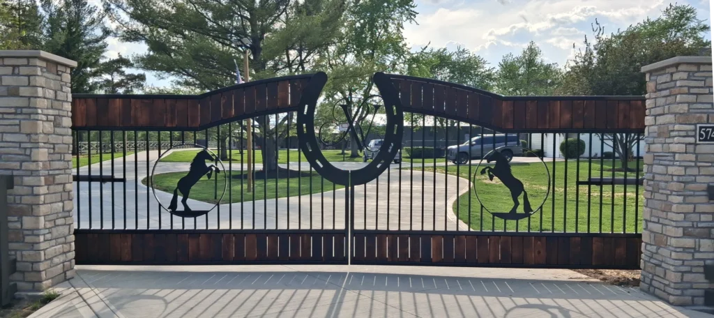 Custom Steel Driveway Gates 1 Custom dual swing cedar wood and black metal driveway gate with plasma cut horse silhouettes on a ranch estate.